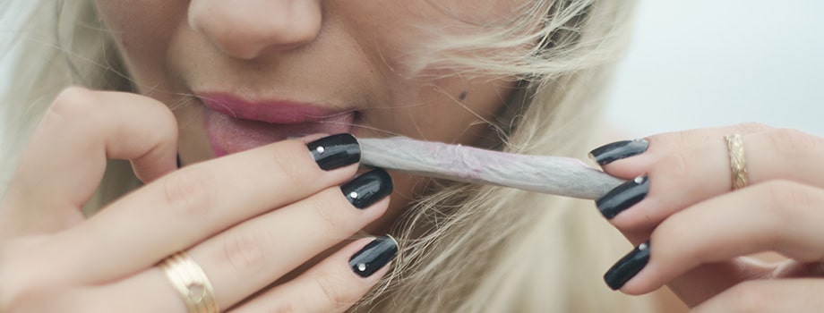 female licking a joint while rolling.