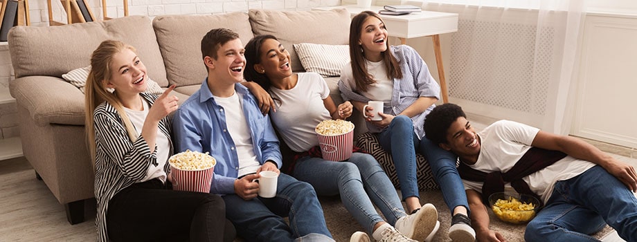 Happy friends watching comedy film and eating popcorn. can you buy edibles online? Where can i buy marijuana edibles online?