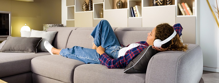 Young woman relaxing on a sofa listening to music. best indica strains in canada. pure indica strains in canada.